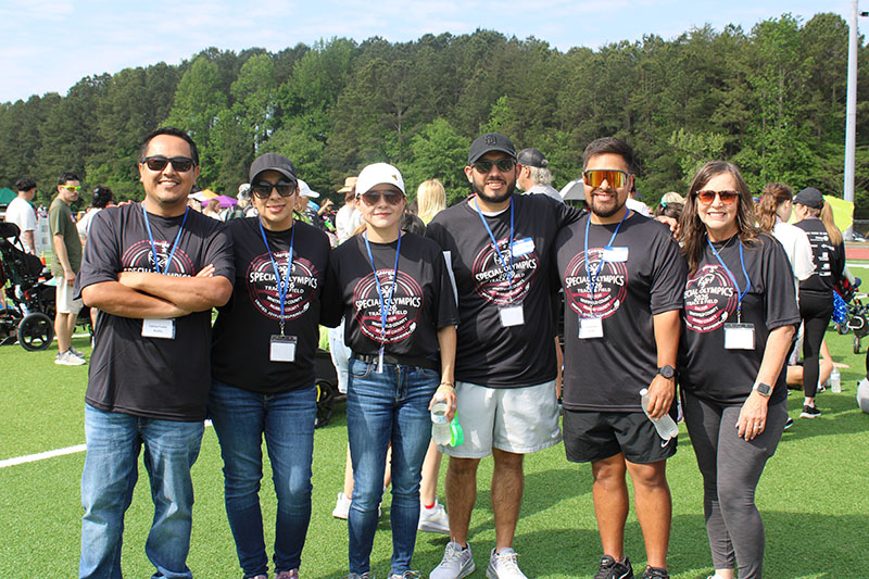 A group of six EF employees posing outdoors after volunteering at a special olympics event, wearing Georgia Special Olympics t-shirts.